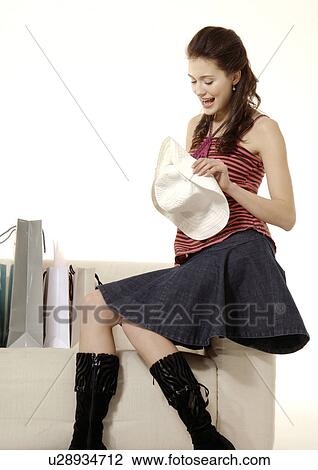 Portrait of a woman sitting on a couch and looking at her purchase. View Large Photo Image Stock Image - Portrait of a woman sitting on a couch and looking at her purchase.. Fotosearch