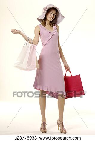 Stock Image - Portrait of a young woman posing with her shopping bags.. Fotosearch