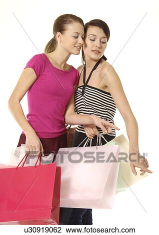 Stock Image - Portrait of two young women with their shopping bags.. Fotosearch