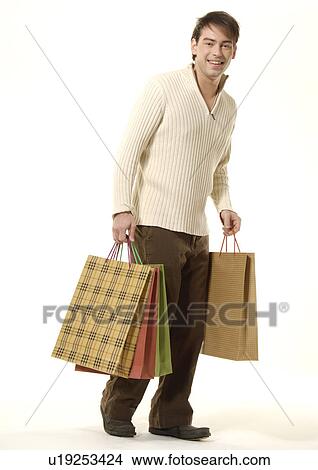 Side view of a young man carrying shopping bags. View Large Photo Image Picture - Side view of a young man carrying shopping bags.. Fotosearch