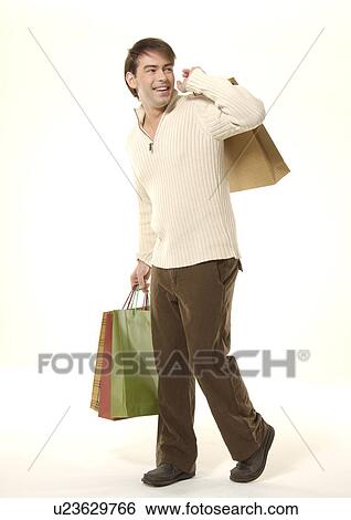 Stock Photograph - Side view of a young man carrying shopping bags.. Fotosearch