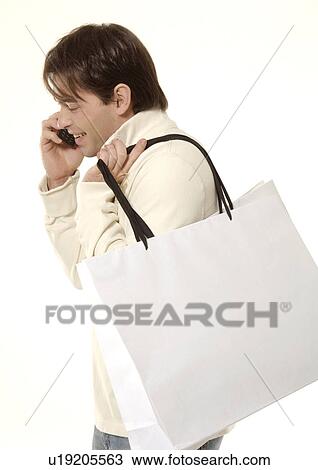 Stock Image - Side view of a young man talking on his cellphone.. Fotosearch