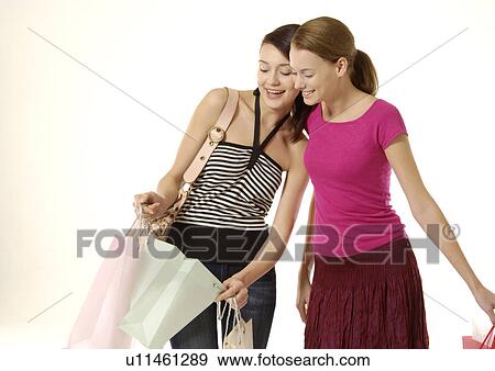 Stock Photo - View of two friends looking in to their shopping bags.. Fotosearch