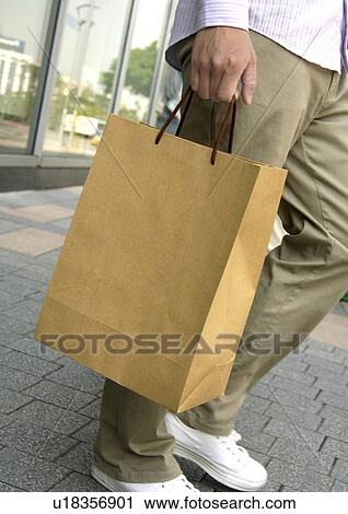 Cropped view of a man holding a carrier bag. View Large Photo Image Stock Image - Cropped view of a man holding a carrier bag.. Fotosearch
