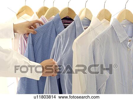 Picture - Cropped view of a person selecting the shirts.. Fotosearch