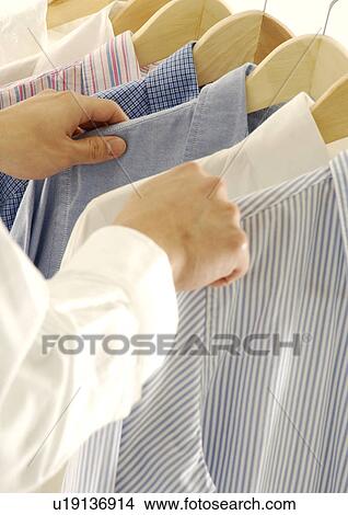 Cropped view of a woman selecting a shirt. View Large Photo Image Picture - Cropped view of a woman selecting a shirt.. Fotosearch