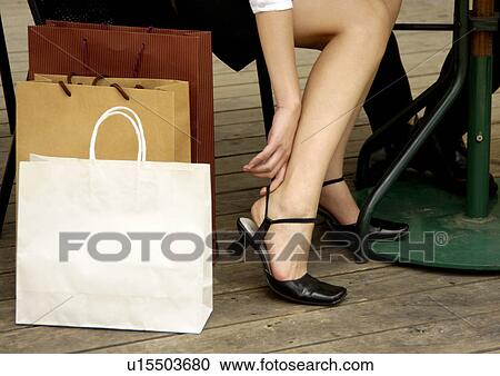 Stock Image - Cropped view of a woman wearing her sandals.. Fotosearch