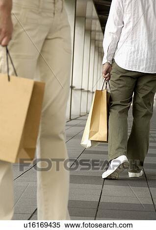 Cropped view of two people holding carrier bags. View Large Photo Image Stock Photography - Cropped view of two people holding carrier bags.. Fotosearch
