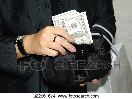 View of a woman holding a purse filled with money. View Large Photo Image Picture - View of a woman holding a purse filled with money.. Fotosearch