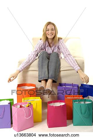 Picture - View of a young woman with colorful shopping bags placed in front of her.. Fotosearch