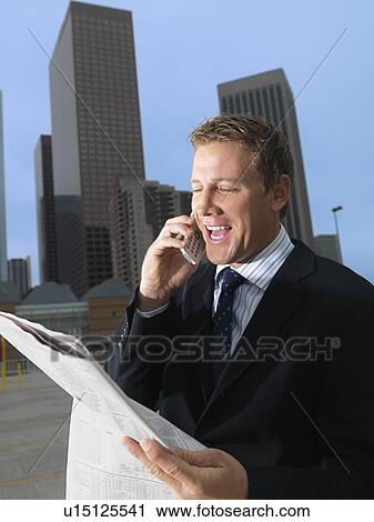 A Mid Adult Businessman Holding a Newspaper and Talking on a Cellular Phone, Waist Up View Large Photo Image Stock Image - A Mid Adult Businessman Holding a Newspaper and Talking on a Cellular Phone, Waist Up. Fotosearch