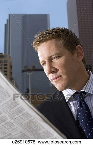 Stock Photo - A Mid Adult Businessman Reading a Newspaper, Front View, Head and Shoulders. Fotosearch