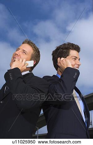 A Pair of Businessman Talking on a Cellular Phone, Waist Up, Low Angle View View Large Photo Image Stock Image - A Pair of Businessman Talking on a Cellular Phone, Waist Up, Low Angle View. Fotosearch