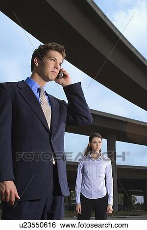 Stock Photograph - A Pair of Office Workers Standing by the Elevated Roads, Three Quarter Length, Low Angle View. Fotosearch