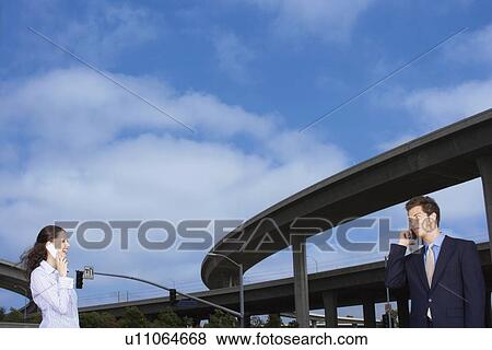 A Pair of Office Workers Talking on a Cellular Phone, Low Angle View, Waist Up View Large Photo Image Stock Photo - A Pair of Office Workers Talking on a Cellular Phone, Low Angle View, Waist Up. Fotosearch