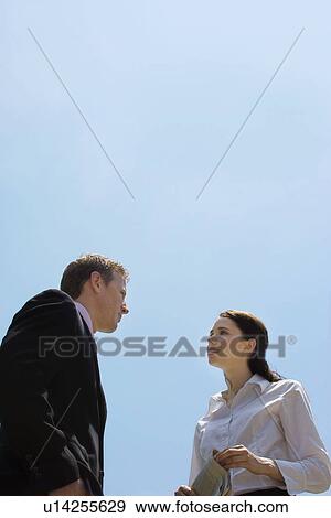 Stock Photo - A Pair of Talking Office Workers, Low Angle View, Waist Up. Fotosearch