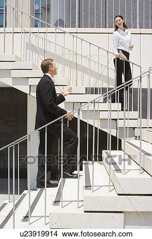 A Pare of Office Workers Talking on the Stairs, Side View, Full Length View Large Photo Image Picture - A Pare of Office Workers Talking on the Stairs, Side View, Full Length. Fotosearch