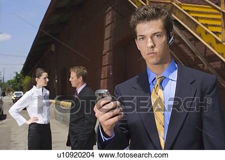 Picture - A Young Adult Businessman Using a Headset Cellular Phone, Front View, Waist Up. Fotosearch