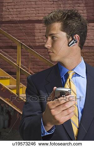 A Young Adult Businessman Using a Headset Cellular Phone, Waist Up View Large Photo Image Stock Photograph - A Young Adult Businessman Using a Headset Cellular Phone, Waist Up. Fotosearch