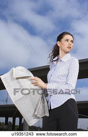 A Young Adult Businesswoman Holding a Newspaper, Three Quarter Length, Low Angle View View Large Photo Image Stock Image - A Young Adult Businesswoman Holding a Newspaper, Three Quarter Length, Low Angle View. Fotosearch