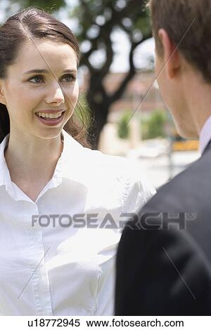 Stock Photography - A Young Adult Businesswoman Talking with a Businessman, Differential Focus, Waist Up, Front View. Fotosearch