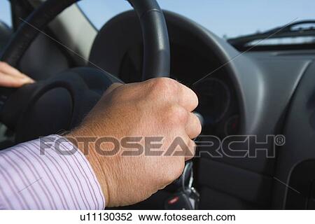 Stock Image - Closed Up Image of Hands Holding a Steering Wheel, Differential Focus. Fotosearch