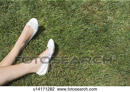 Stock Image - Woman's Legs resting on grass, High Angle View, Copy Space. Fotosearch