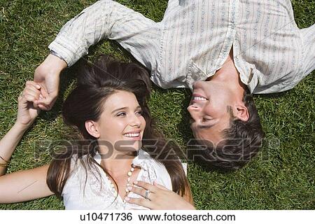 Young adult couple lying down on grass, High Angle View View Large Photo Image Stock Photograph - Young adult couple lying down on grass, High Angle View. Fotosearch