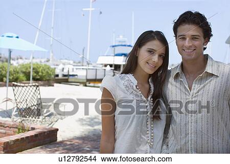 Young adult couple smiling at camera, Front View, Differential Focus View Large Photo Image Picture - Young adult couple smiling at camera, Front View, Differential Focus. Fotosearch