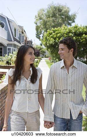 Stock Image - Young adult couple walking together, Front View. Fotosearch