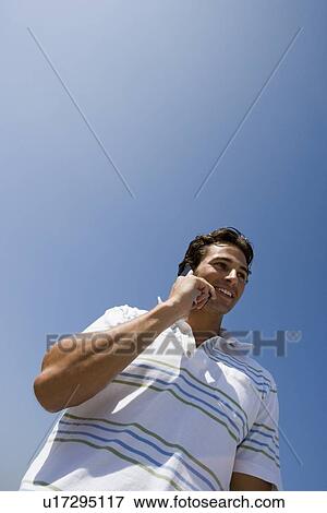 Young adult man talking on mobile phone, Low Angle View, Copy Space View Large Photo Image Stock Photo - Young adult man talking on mobile phone, Low Angle View, Copy Space. Fotosearch