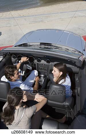 Stock Photo - Young adult people on a convertible car, Rear View, High Angle View. Fotosearch