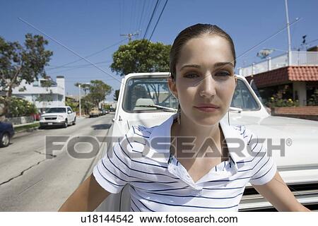 Young adult woman looking at camera and standing in front of a car, Front View View Large Photo Image Stock Image - Young adult woman looking at camera and standing in front of a car, Front View. Fotosearch