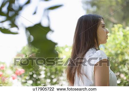 Stock Image - Young adult woman looking away, Side View, Low Angle View, Differential Focus. Fotosearch