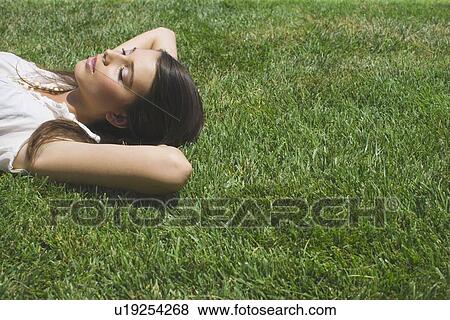 Young adult woman lying down on grass, Side View, High Angle View, Copy Space View Large Photo Image Stock Photo - Young adult woman lying down on grass, Side View, High Angle View, Copy Space. Fotosearch
