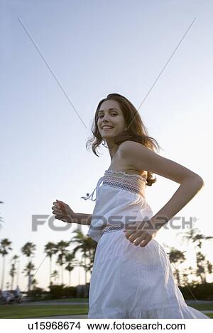 Picture - Young adult woman smiling and running, Side View, Low Angle View, Differential Focus, Copy Space. Fotosearch