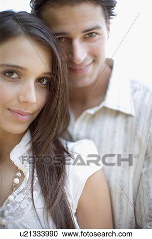 Stock Image - Young adult woman smiling at camera, Front View, Differential Focus. Fotosearch