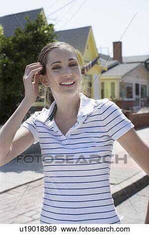 Stock Photo - Young adult woman smiling at camera, Front View, Differential Focus. Fotosearch