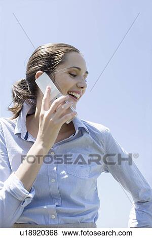 Young adult woman talking on mobile phone, Low Angle View View Large Photo Image Stock Photo - Young adult woman talking on mobile phone, Low Angle View. Fotosearch