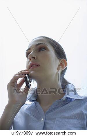 Stock Photo - Young adult woman talking on mobile phone, Low Angle View, Differential Focus. Fotosearch