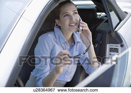 Young adult woman talking on mobile phone in car, High Angle View View Large Photo Image Stock Photo - Young adult woman talking on mobile phone in car, High Angle View. Fotosearch
