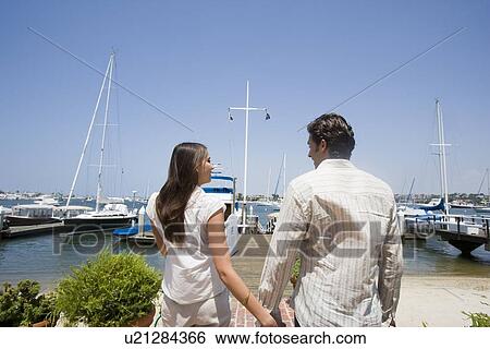 Stock Photograph - Young adult couple in yacht basin, Rear View. Fotosearch
