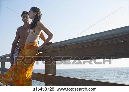 Stock Photo - Young adult couple leaning on railing, Side View, Low Angle View. Fotosearch