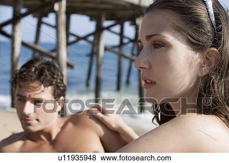 Stock Photo - Young adult couple on beach, Side View, Differential Focus. Fotosearch