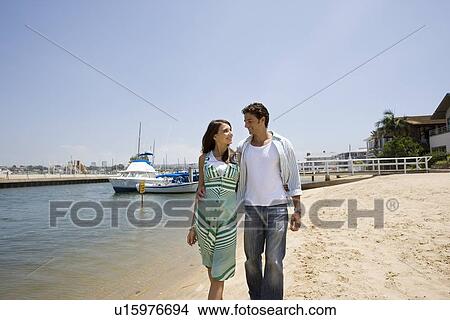 Young adult couple walking on beach, Front View View Large Photo Image Picture - Young adult couple walking on beach, Front View. Fotosearch