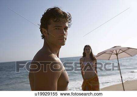 Young adult man looking at camera and woman standing behind, Front View, Side View, Differential Focus View Large Photo Image Stock Photography - Young adult man looking at camera and woman standing behind, Front View, Side View, Differential Focus. Fotosearch