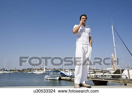 Young adult man talking on mobile phone, Low Angle View, Copy Space View Large Photo Image Picture - Young adult man talking on mobile phone, Low Angle View, Copy Space . Fotosearch