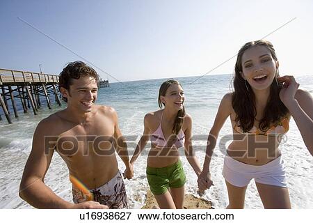 Stock Photo - Young adult people having fun on beach, Front View. Fotosearch