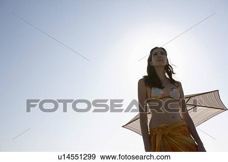 Stock Photo - Young adult woman looking away on beach, Low Angle View, Copy Space . Fotosearch