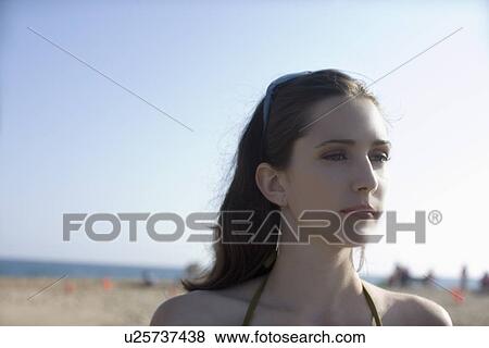 Stock Photo - Young adult woman looking away on beach, Side View, Differential Focus, Copy Space . Fotosearch